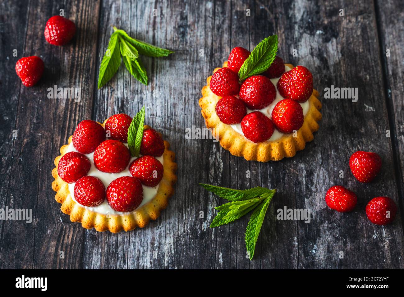 Hausgemachte Erdbeertörtchen auf rustikalem dunklen Holztisch Stockfoto