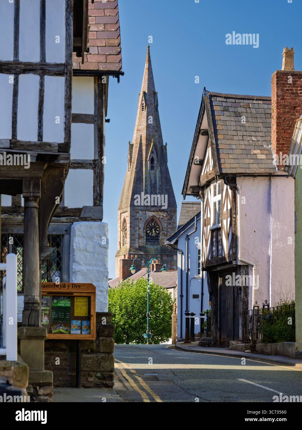 Straßenecke mit Blick auf eine Gasse in Richtung eines entfernten St. Peters Kirchturms in der Stadt Ruthin, Nordwales Stockfoto