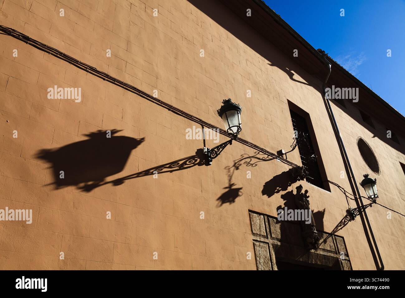 Alte Lichter werfen lange Schatten auf eine Wand des Sant Joan de Hospital in Valencia Spanien Stockfoto