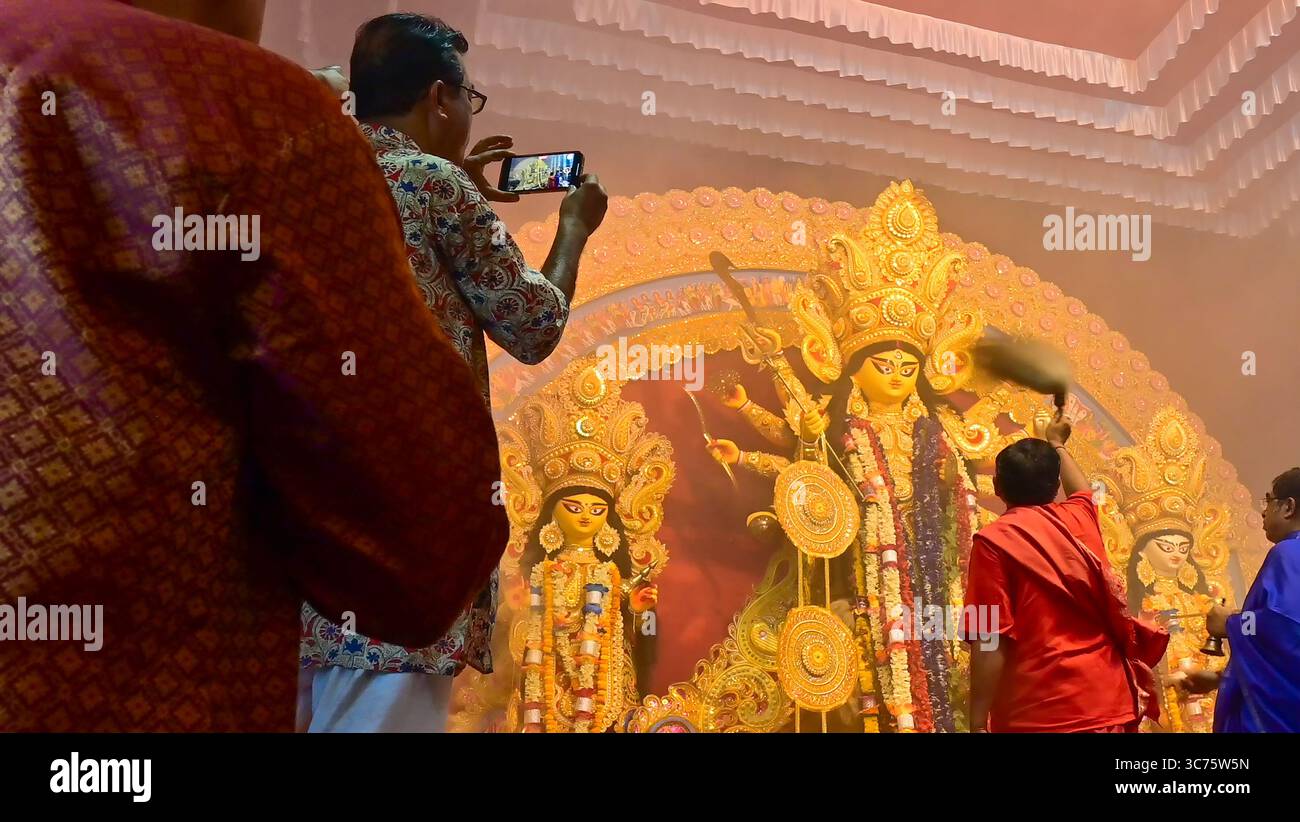 Howrah, Westbengalen, Indien -11.10.2024 : ein Anhänger macht Fotos, während die Hindu-Purohten während des Sondhipujo die Göttin Durga anbeten. Stockfoto