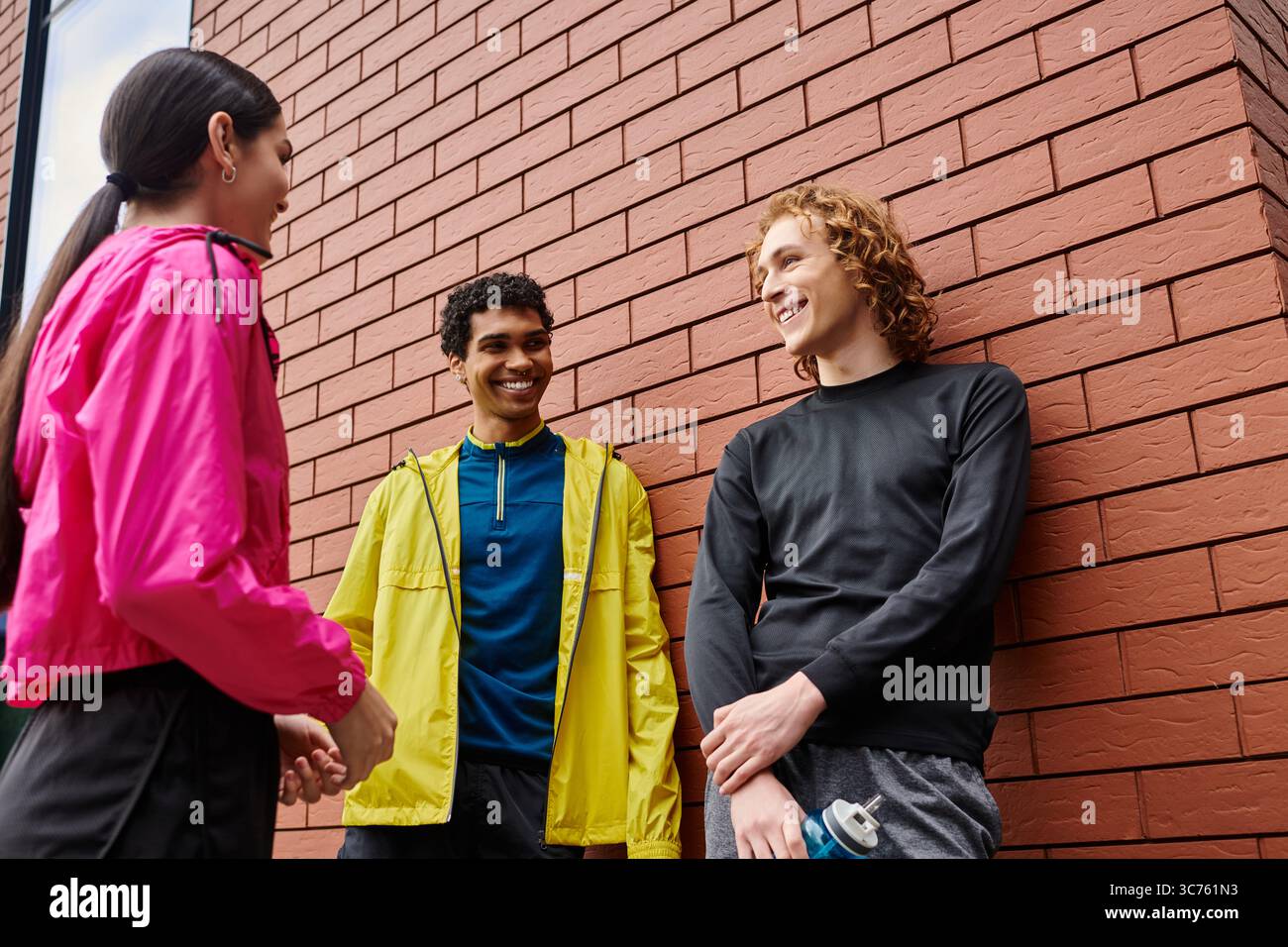 Drei sportliche Personen unterhalten sich während ihres Outdoor-Trainings miteinander und lachen. Stockfoto