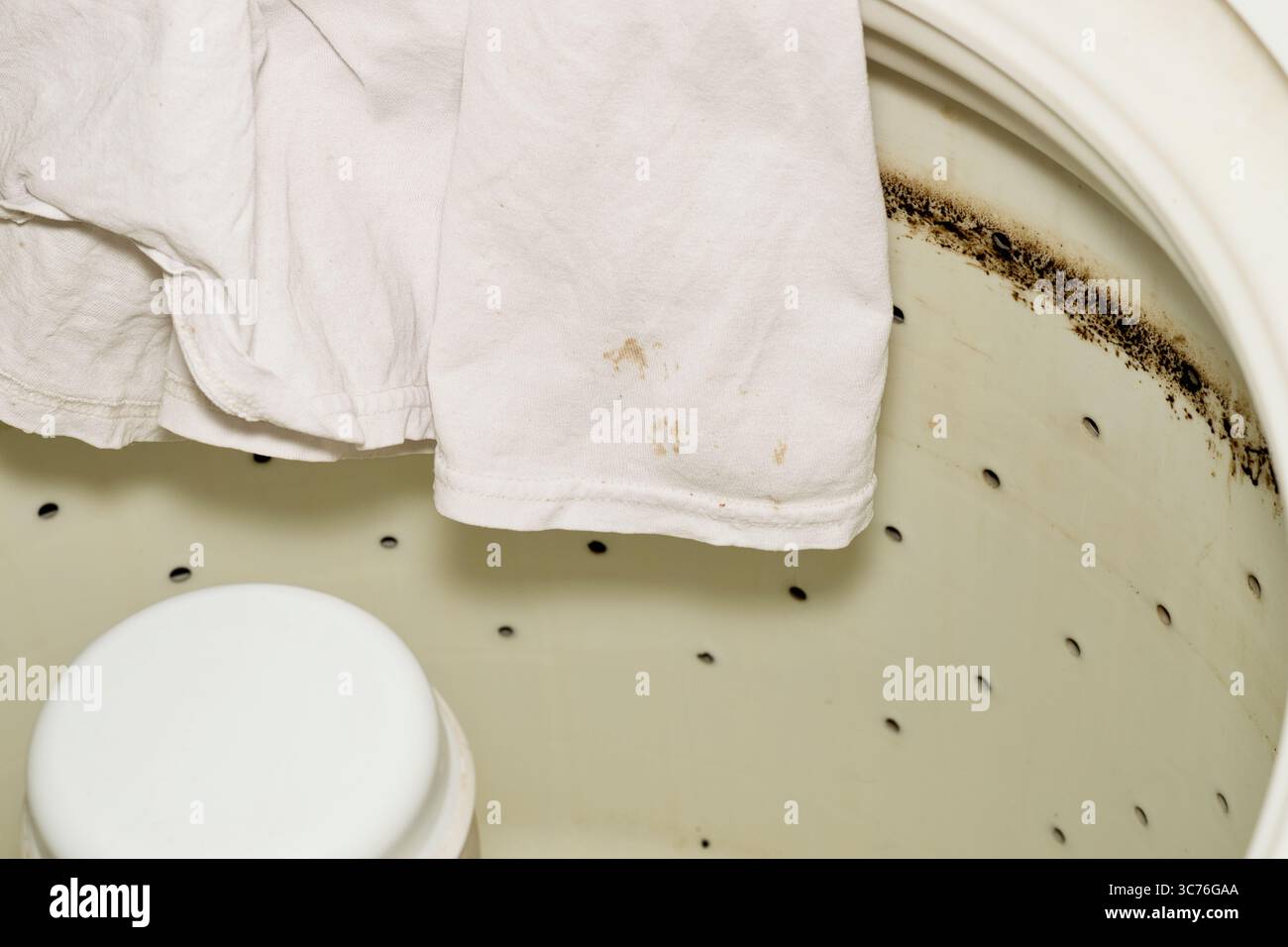 Defekter, verschmutzter Ölring der Waschmaschine und Fettflecken, weißes Hemd. Stockfoto