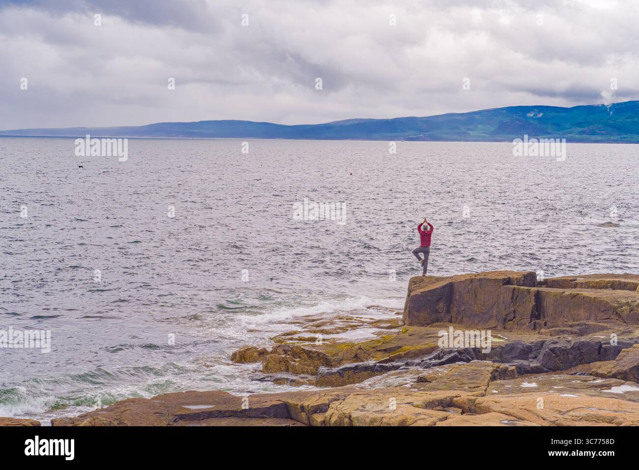 Coastal Yoga Serenity wird im Acadia-Nationalpark entlang der Küste von Maine festgehalten. Der einzelne findet Gleichgewicht inmitten der zerklüfteten Küste und beruhigend Stockfoto
