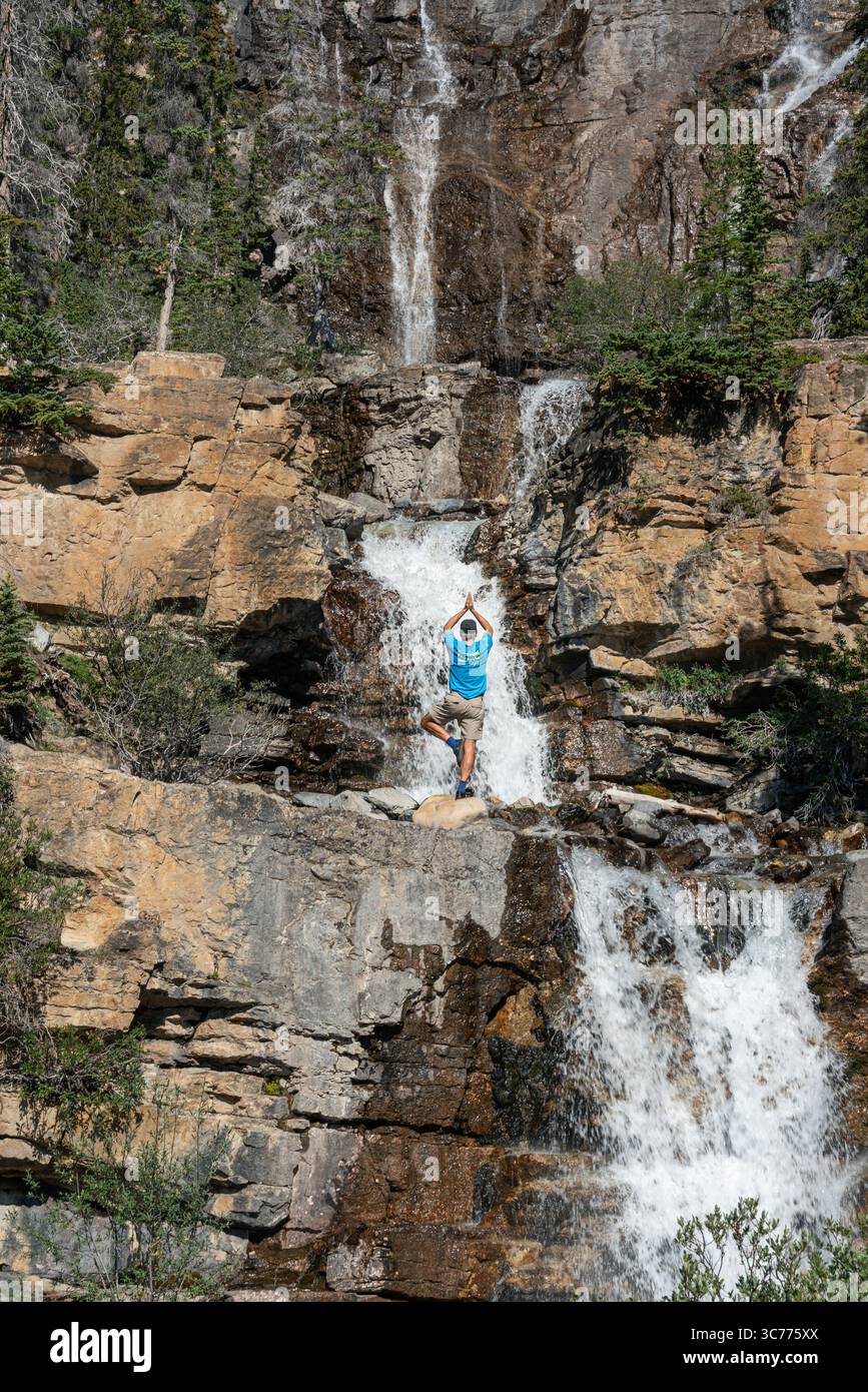 Wasserfall Yoga Serenity: Ein Besucher findet innere Ruhe mit einer Yoga-Pose an einem Wasserfall im Jasper National Park. Der Park liegt im Canadian Rock Stockfoto