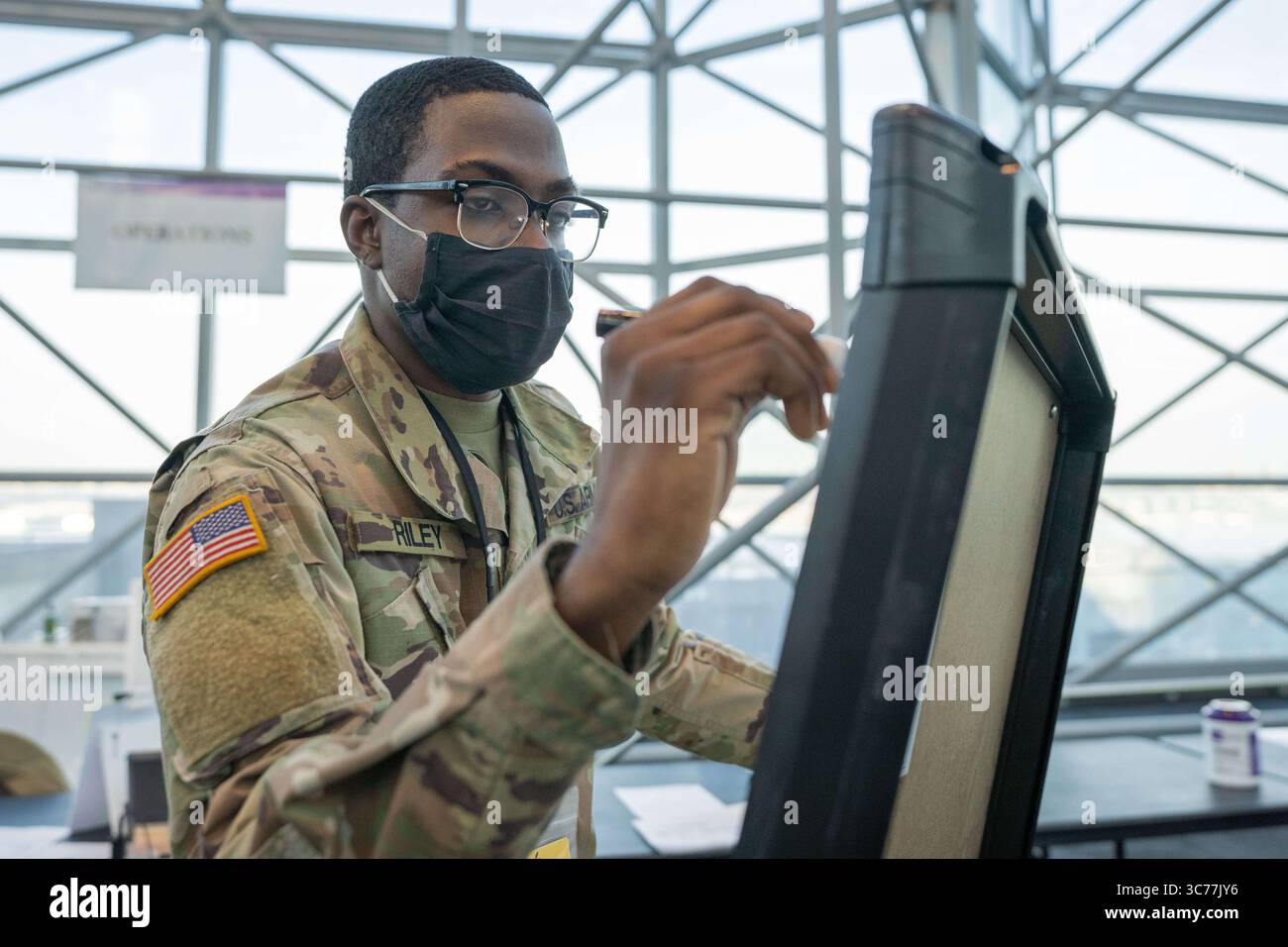 14. Januar 2021 – New York, New York, USA – SPC der US-Armee George Riley, ein für die Überwachung und Wartung von Spezialunterstützungssystemen zuständiger Werkstattbetrieb für Versorgungseinrichtungen, der der 719th Composite Truck Company, 369th Sustainment Brigade, zugewiesen wurde, zeichnet am 14. Januar 2021 am Javits Convention Center in Manhattan (New York) Einsatznachverfolgungstabellen zur Unterstützung von COVID-19-Massenimpfungen, die vom New York State Department of Health durchgeführt werden. (Kreditbild: © Sebastian Rothwyn/U.S. Army/ZUMA Wire/ZUMAPRESS.com) Stockfoto