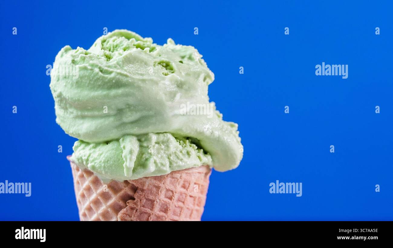 Ein erfrischender Löffel Matcha-Grüntee-Eis mit blauem Hintergrund Stockfoto