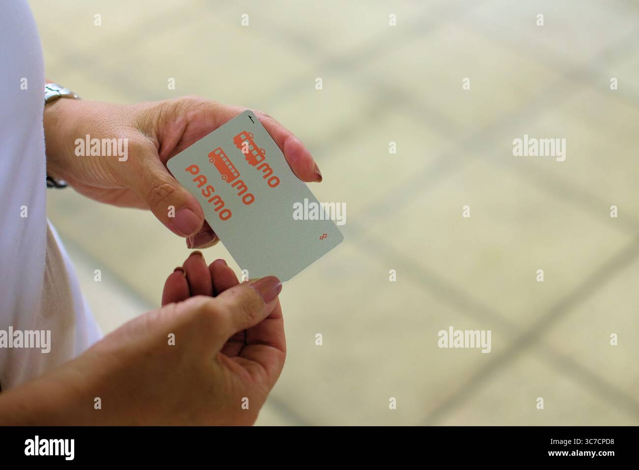 Die Hände einer Frau halten eine Pasmo-Karte; aufladbare, kontaktlose Smart Card für öffentliche Verkehrsmittel und Einkaufsmöglichkeiten in Tokio, Japan. Stockfoto