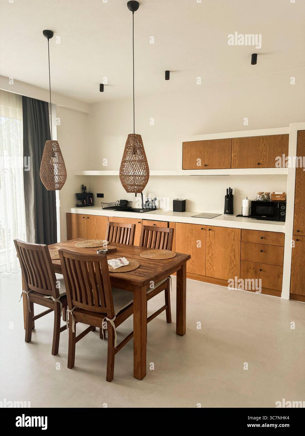 Moderne Kücheneinrichtung mit Holzmöbeln und stilvollen Beleuchtungselementen Stockfoto