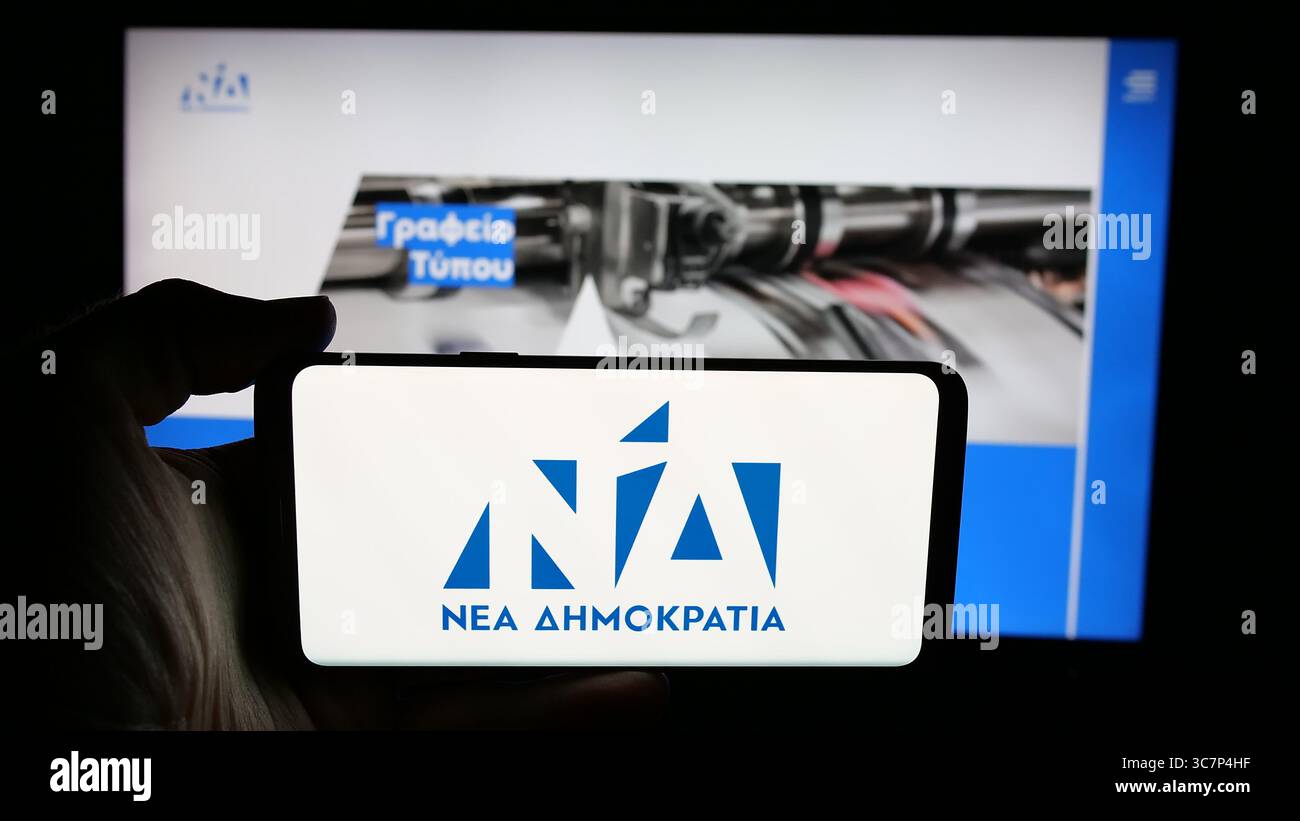 Stuttgart, Deutschland - 18.07.2025: Person mit Handy mit Logo der griechischen politischen Partei Nea Dimokratia (ND) auf dem Bildschirm vor der Webseite. Stockfoto