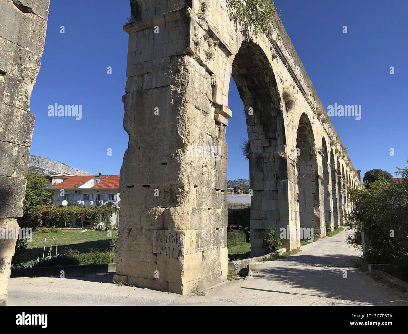 Ein altes Aquädukt aus Stein erstreckt sich bis in den blauen Himmel, Diokletian's Aquädukt, Split, Kroatien Stockfoto