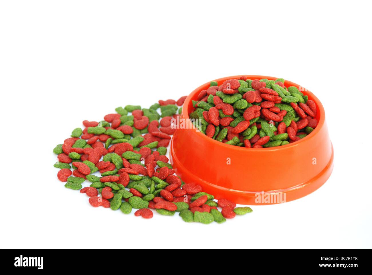 Hellorangefarbene Futterschale gefüllt mit rotem und grünem katzenförmigem Trockenfutter auf weißem Hintergrund. Stockfoto