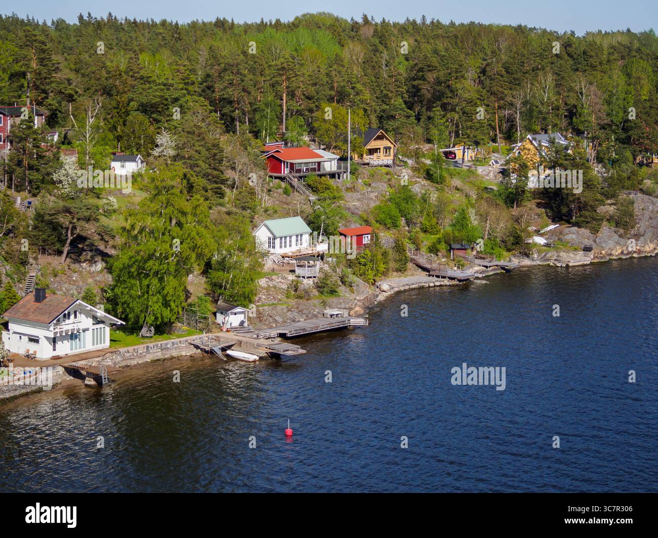 Traditionelle schwedische Ferienhütten auf Inseln von der Schifffahrtsroute aus gesehen. Diese kleinen Häuser werden üblicherweise von Stockholmers als Wochenendrückzugsort genutzt Stockfoto