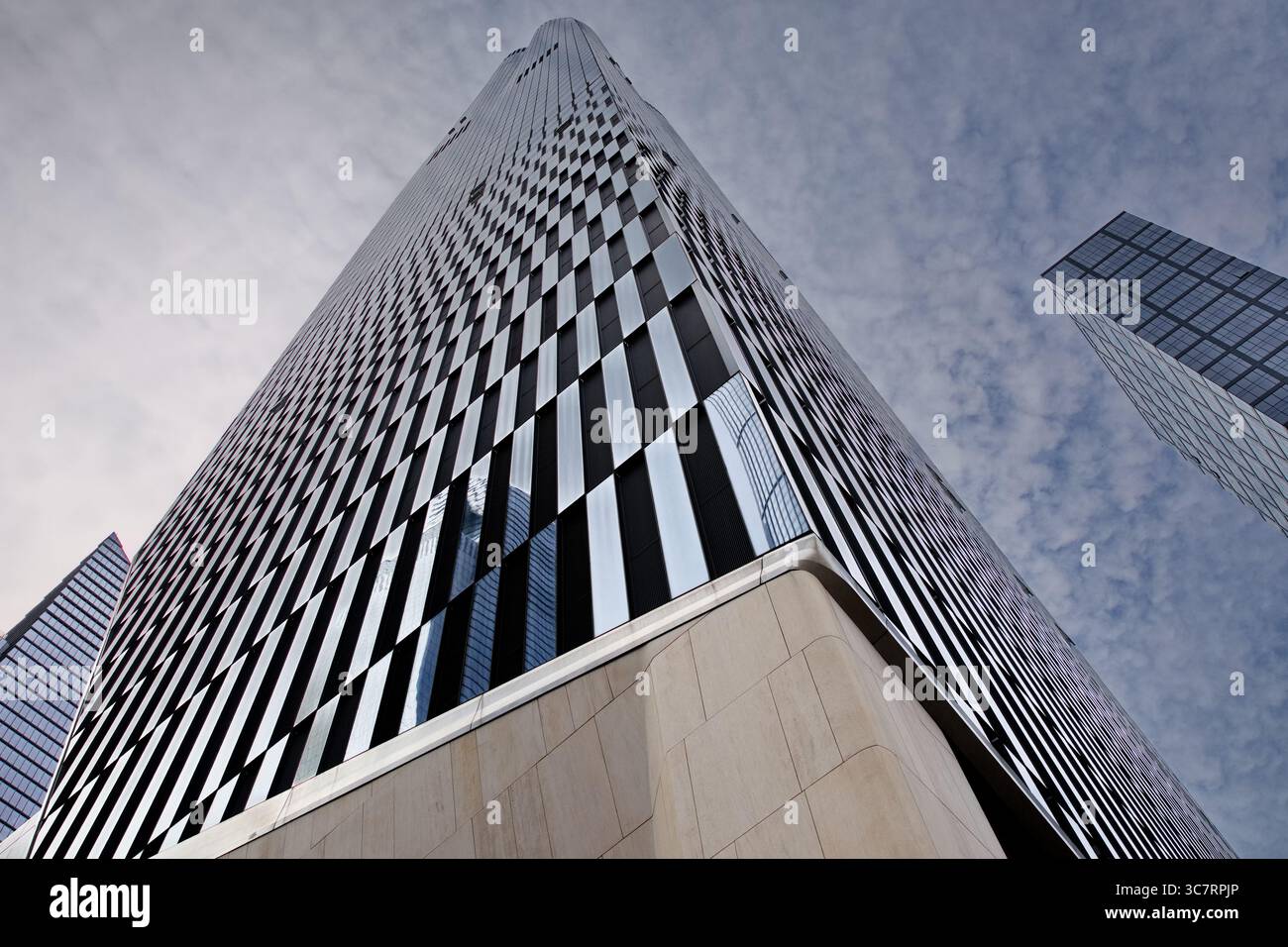 Bewundern Sie die hoch aufragende Glasfassade von 35 Hudson Yards auf Manhattans West Side, die die pulsierende urbane Skyline und die zeitgenössische Stadtlandschaft darunter reflektiert. Stockfoto