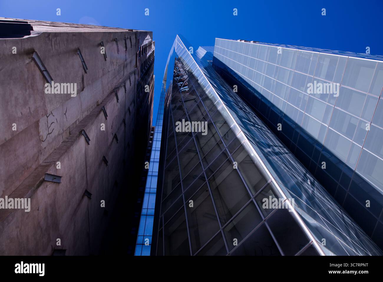 Aufwärtsaufnahme der Wolkenkratzer Manhattans an einem hellen Tag mit reflektierendem Licht, markanten geometrischen Linien und einer riesigen Skyline in New York City. Stockfoto