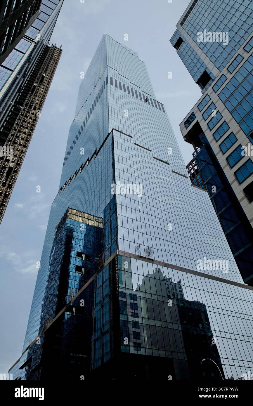 Ein perforierter Glashochhaus in Manhattans Straßenschlucht reflektiert die benachbarten Türme durch seine gepunktete Fassade und zieht das Auge bei Tageslicht in den Himmel. Stockfoto