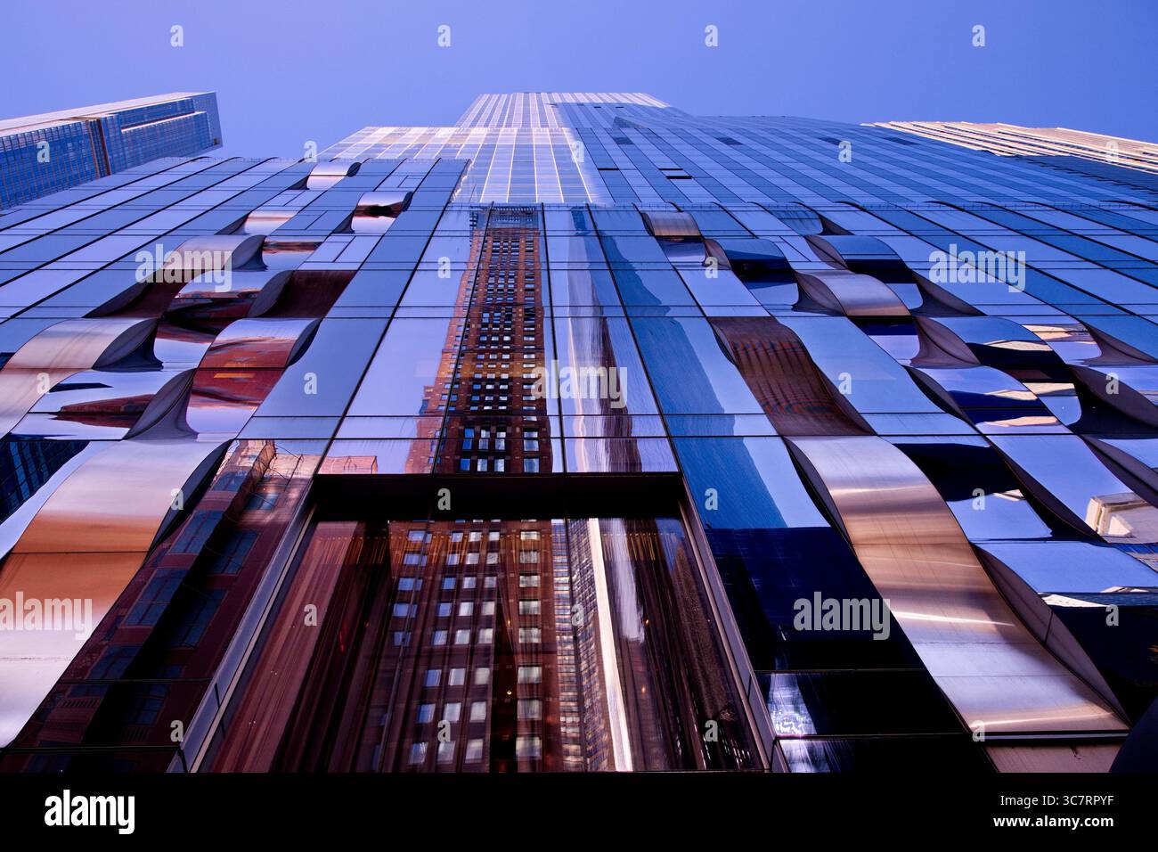 Die Glasfassade der West Street 50 in New York spiegelt die benachbarten Türme und den Turm eines Vanderbilt vor einem leuchtend blauen Himmel in Manhattan wider. Stockfoto