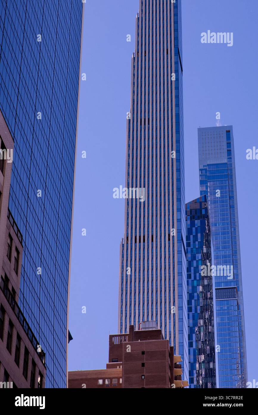 Die schlanke Silhouette des Steinway Tower erhebt sich über dem Straßenschlucht von Midtown Manhattan, dessen gewellte Fassade das Licht vor dem strahlend azurblauen Himmel einfängt. Stockfoto
