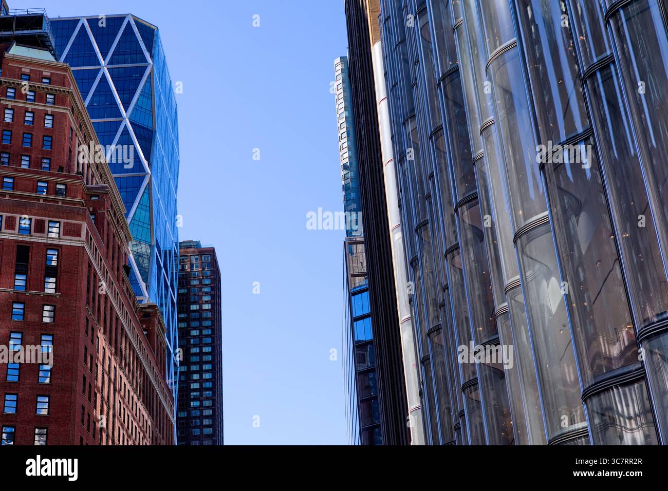 Der charakteristische dreieckige Diagrid des Hearst Tower erhebt sich hinter der Glasfassade der West Street 50 entlang der lebhaften Skyline von Midtown Manhattan. Stockfoto