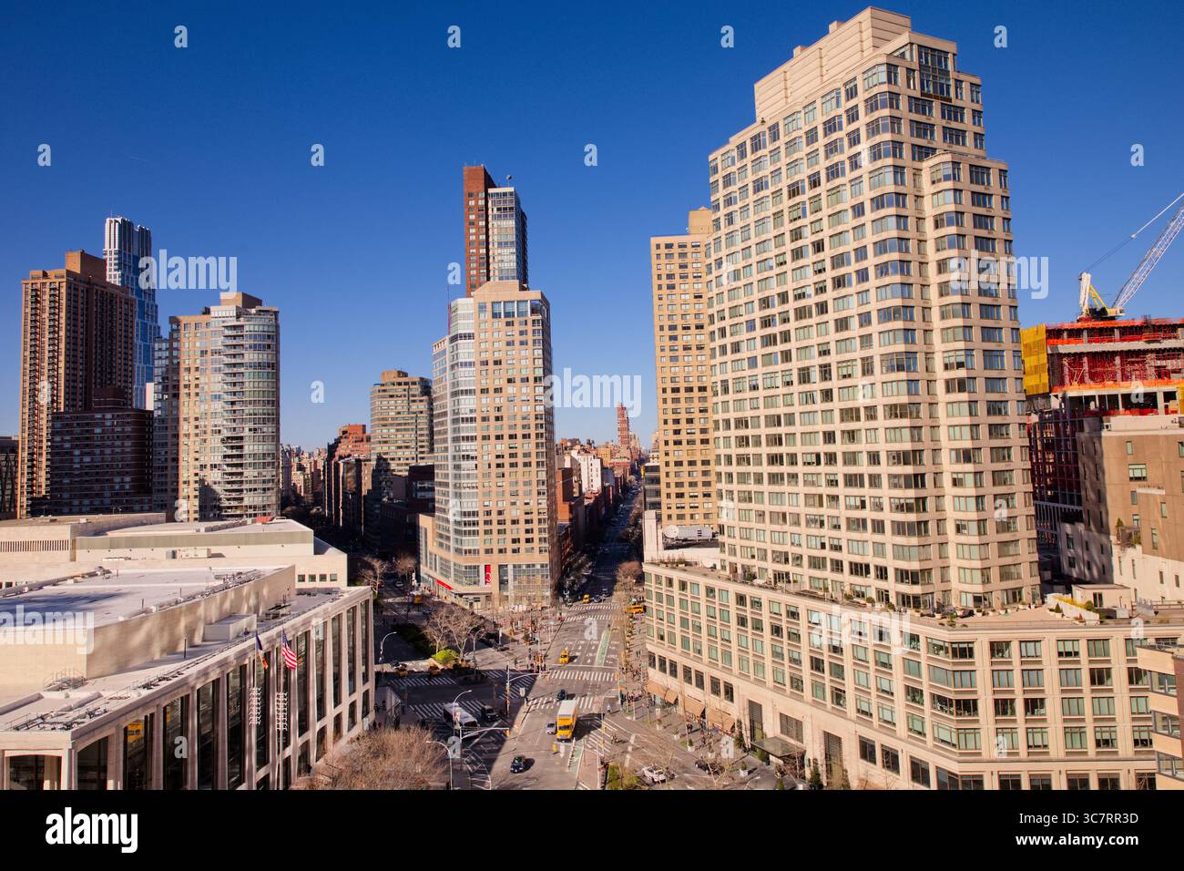 Der Kreisverkehr des Columbus Circle ist von Türmen mit gemischter Nutzung und den Geschäften am Columbus Circle umgeben, die alle unter einem klaren blauen Himmel in klarem Sonnenlicht getaucht sind Stockfoto