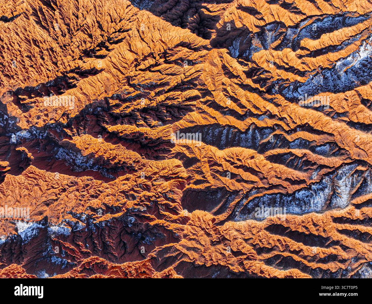 Eine Drohnenperspektive zeigt die markanten natürlichen Muster und Texturen der roten und braunen Hügel im Mars Canyon mit leichtem Schnee Stockfoto