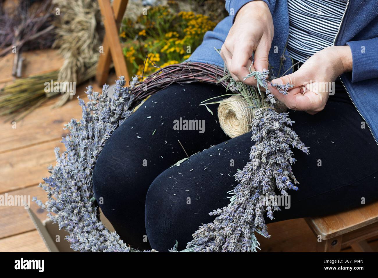 Nahaufnahme der Hände, die Lavendelkranz machen Stockfoto