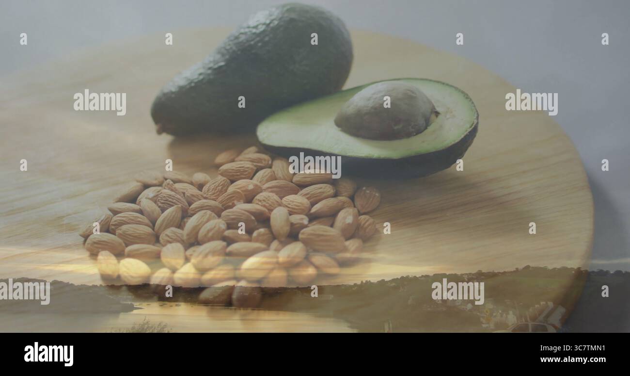 Schneidebrett mit ganzer Avocado, halbierter Avocado, Samen, Mandeln im Studio bei Sonnenuntergang am Fluss Stockfoto