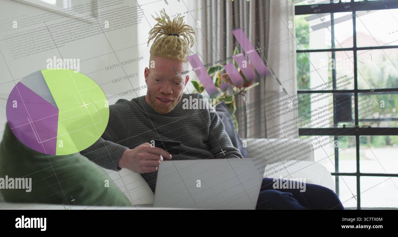 Mit Kreditkarte, Dreadlocked Mann, der auf dem Sofa im Wohnzimmer auf dem Laptop surft, mit Kartenüberlagerungen Stockfoto