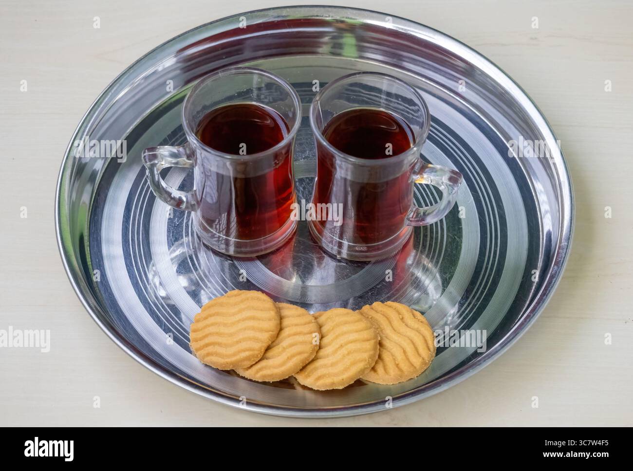 Zwei Tassen schwarzen oder roten Tee auf einer Stahlplatte mit ein paar Keksen. In Bangladesch heißt das Rong Cha oder Lal Cha. Schwarzer Tee ist auch reich an Antioxi Stockfoto