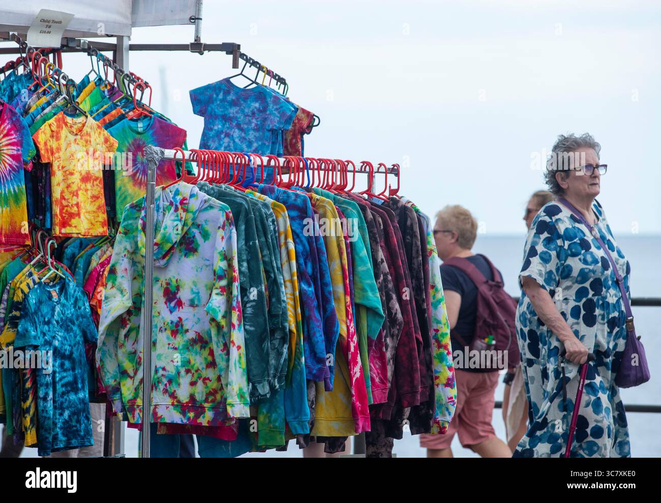 Mehrfarbige Oberteile an einem Stall am Meer in Sidmouth Devon während der Folf Festival Woche. Stockfoto