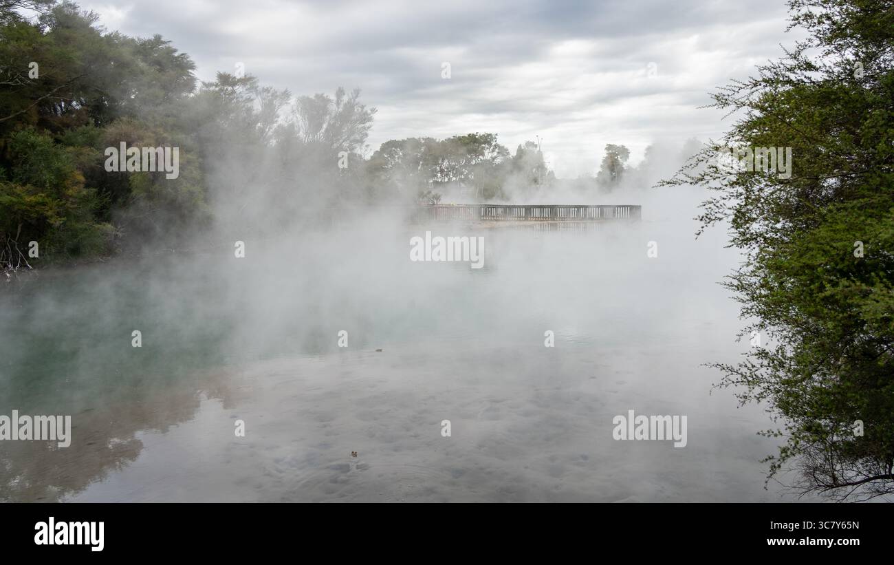 Dampfender heißer geothermischer See mit Aussichtsplattform in der Mitte, Neuseeland Stockfoto