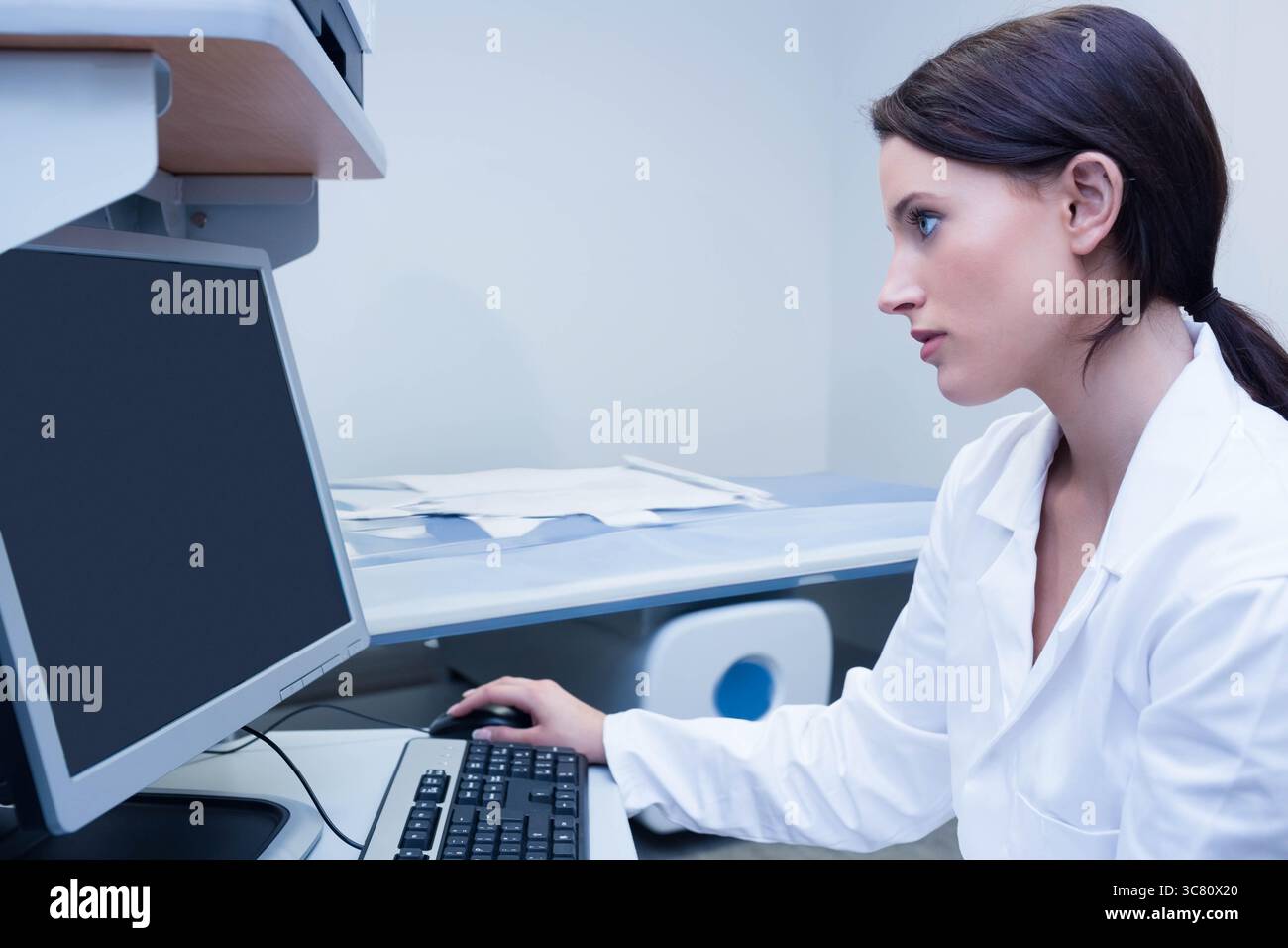 Monitor zeigt Berichte an, Mausklick, Tasten drücken, Papiere liegen verstreut auf dem Schreibtisch im Büro Stockfoto