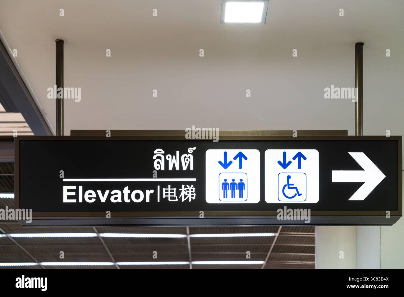 Dies ist ein Richtungsschild, das den Standort des Fahrstuhls anzeigt. Die englische Übersetzung für den thailändischen und chinesischen Text ist Elevator. Stockfoto