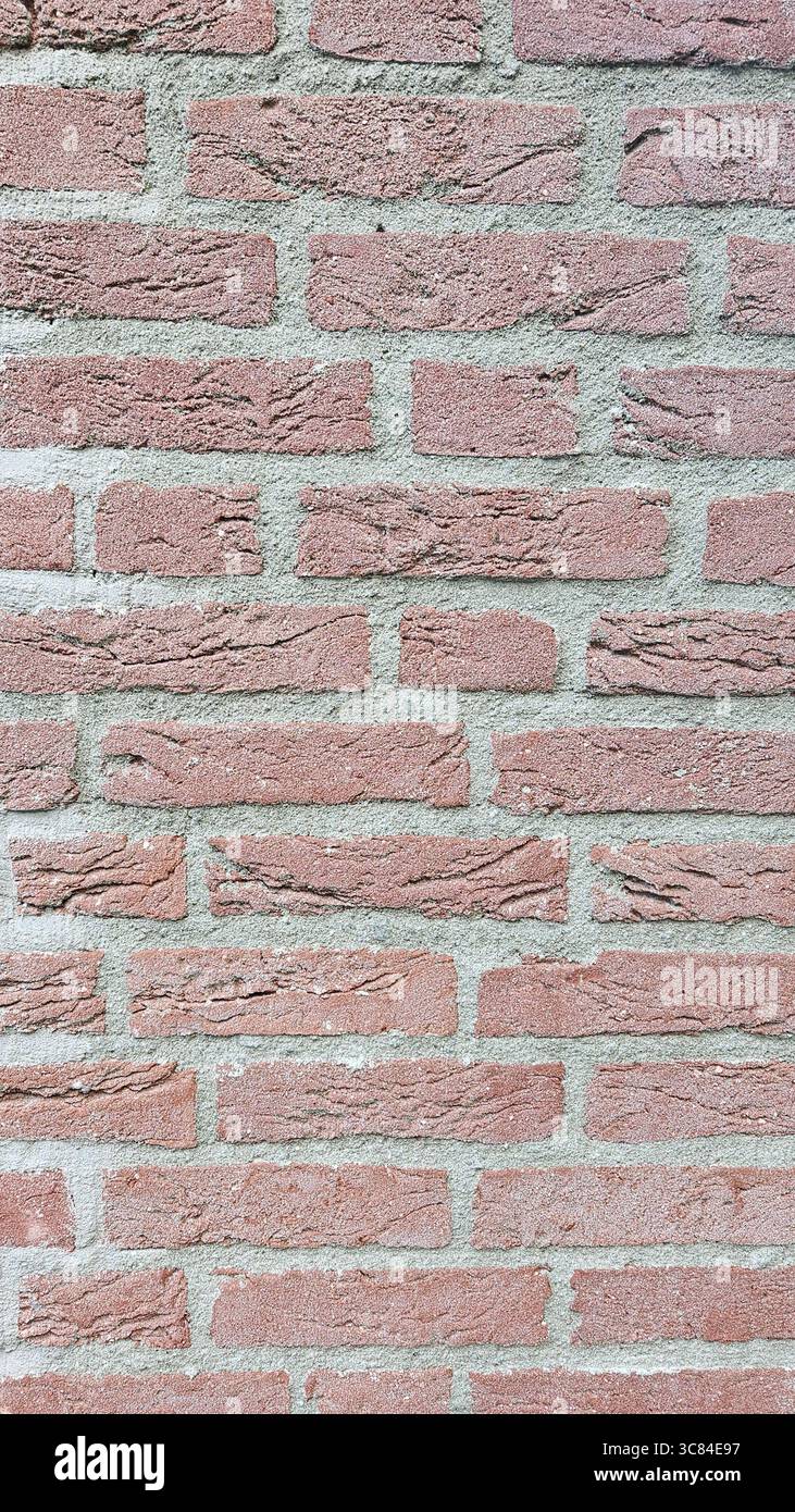 Detaillierte Nahaufnahme einer roten Ziegelwand mit rauer Oberflächenstruktur und grauem Zementmörtel. Ideal für Hintergrund-, Bau- oder Architekturthemen. - Smartphone-aufgenommenes Stockfoto