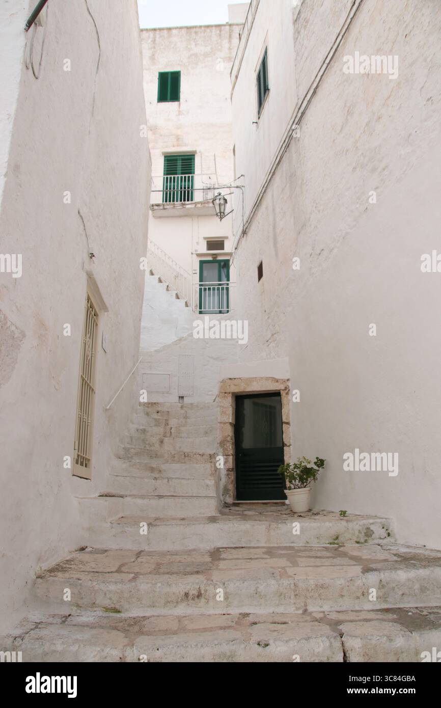 Bezaubernde mediterrane Gasse mit weiß getünchten Wänden, Steintreppen und rustikalen architektonischen Details. Stockfoto