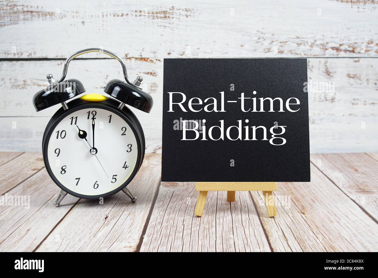 Biettext in Echtzeit mit Staffelei und Wecker auf hölzernem Hintergrund Stockfoto