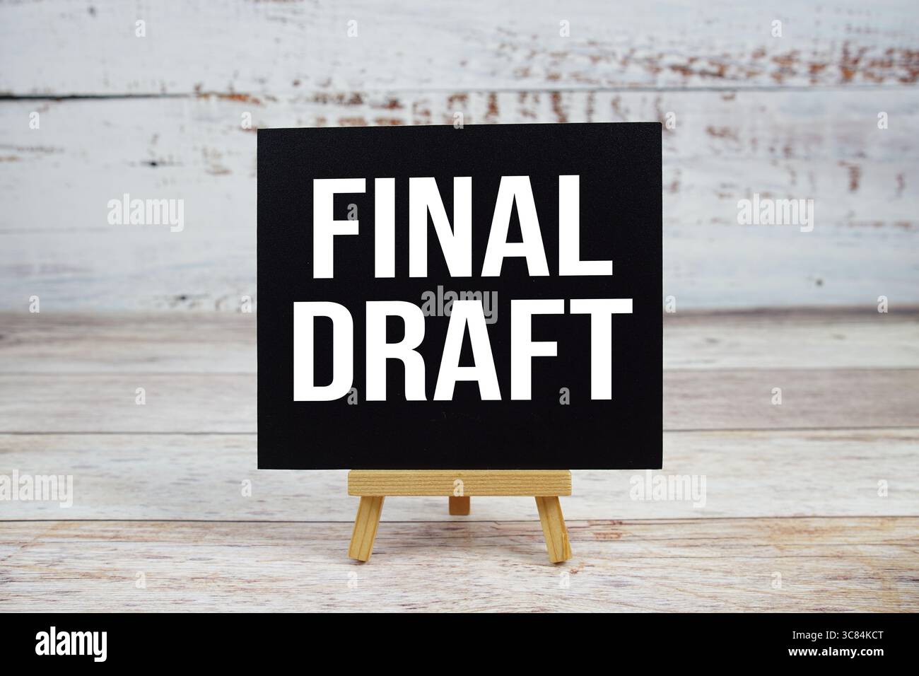Endgültiger Textentwurf mit Staffelei auf hölzernem Hintergrund Stockfoto
