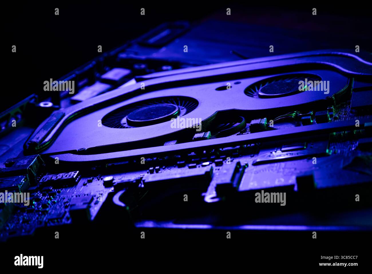 Nahaufnahme eines Hochleistungs-GPU-Kühlsystems mit zwei Lüftern unter dramatischer blauer und grüner Beleuchtung Stockfoto