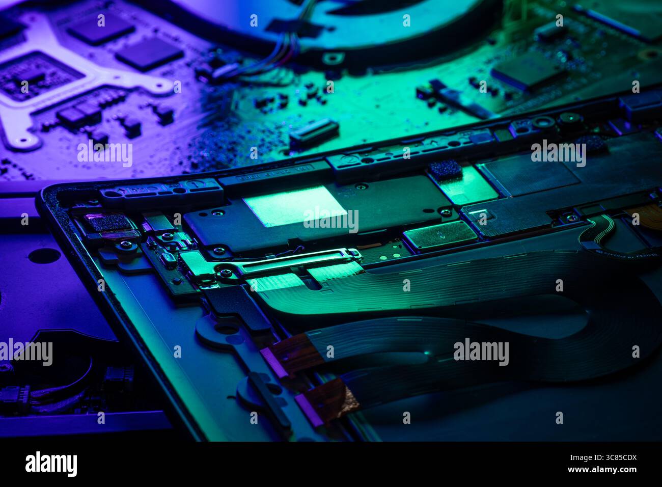 Makroansicht der internen Komponenten des Laptops und der Leiterplatte mit grüner und blauer futuristischer Akzentbeleuchtung Stockfoto