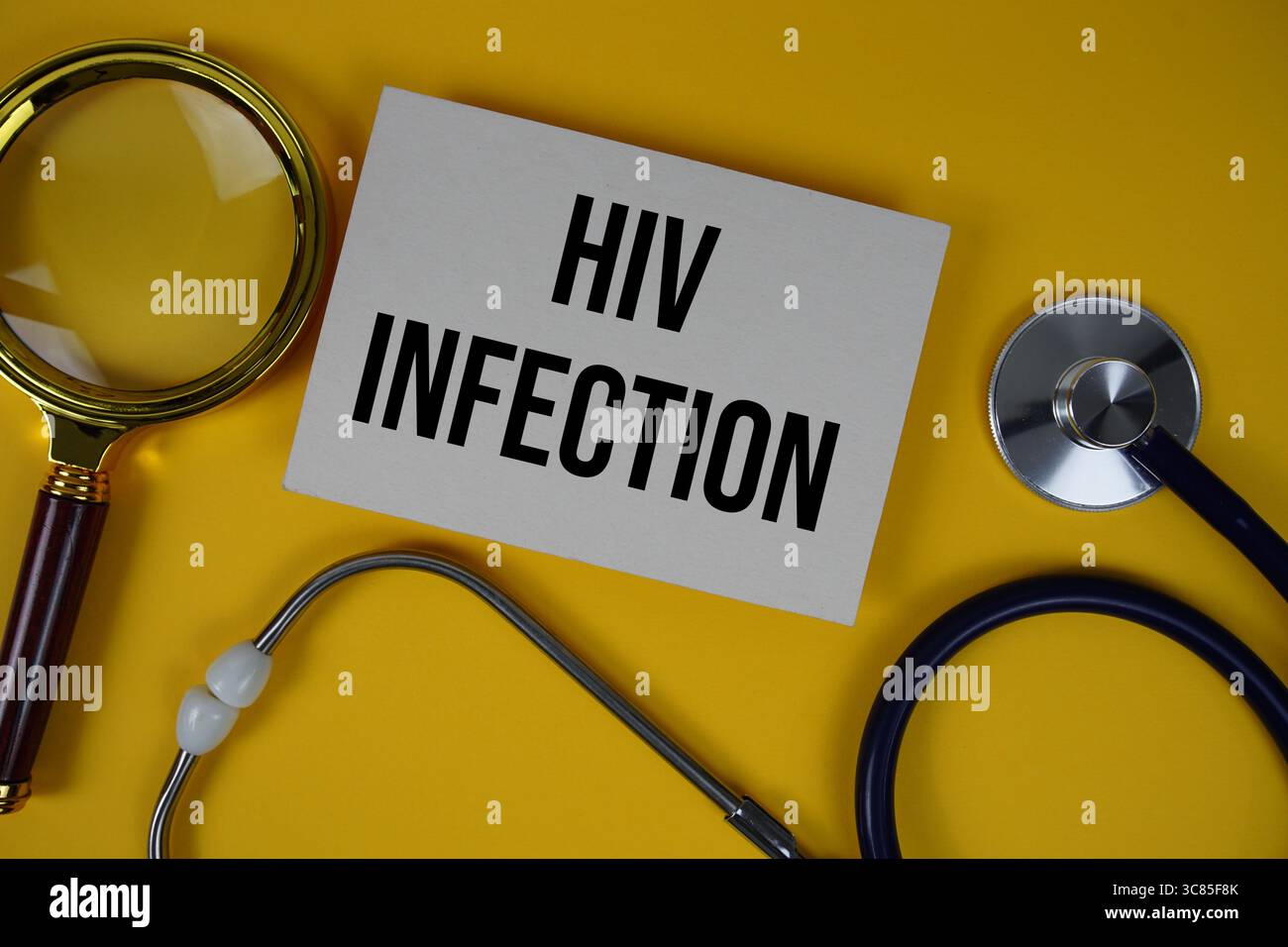HIV-Infektionstext auf Papierkarte mit Stethoskop und Vergrößerungsglas flach auf gelbem Hintergrund Stockfoto
