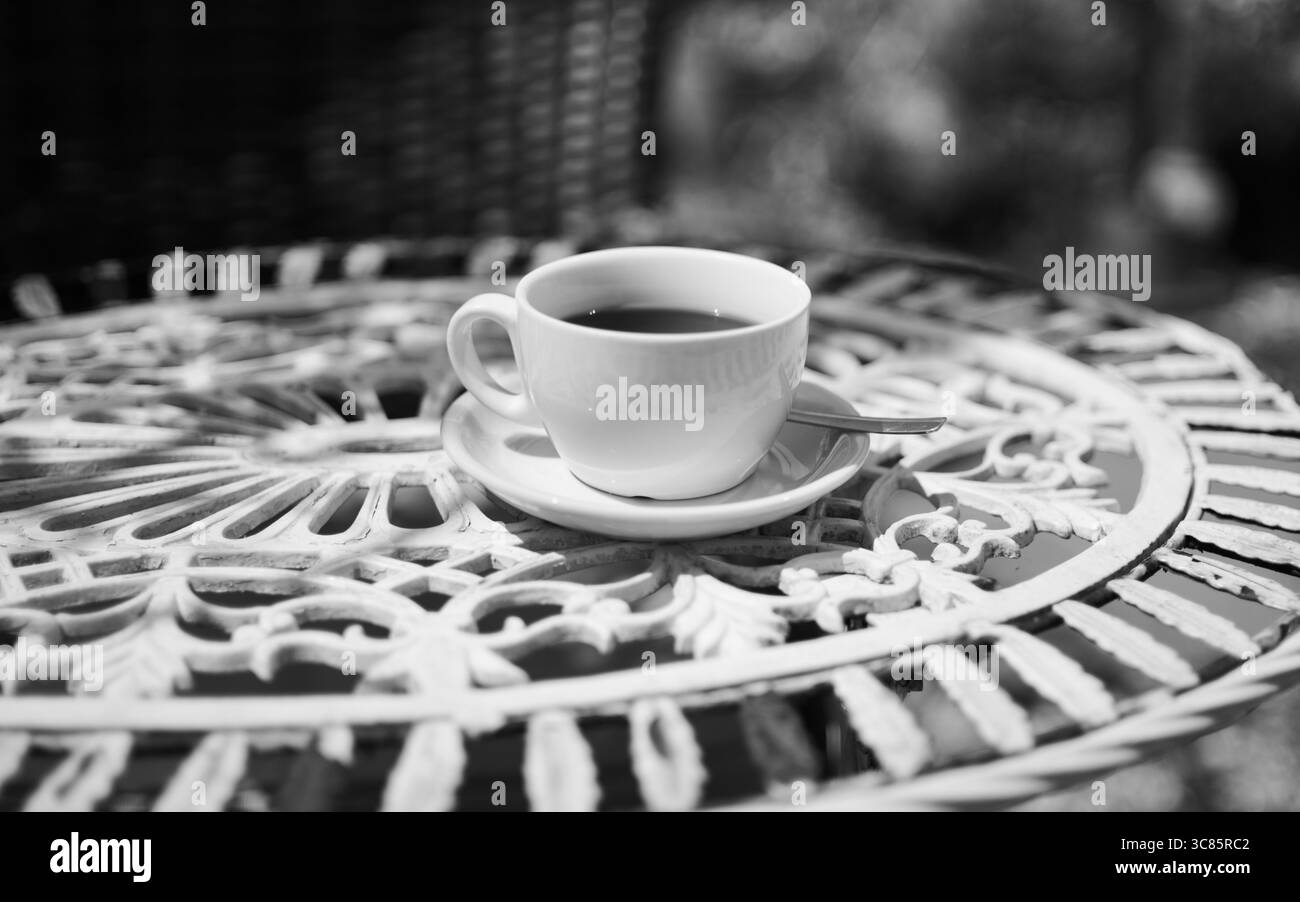 Eine Tasse schwarzen Kaffee in einer weißen Tasse. Auf einem weißen Metalltisch. Stockfoto