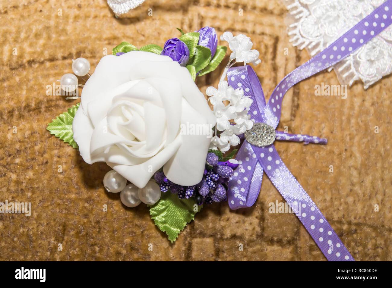 Eine wunderschön angeordnete Corsage mit weißer Rose, zarten lila Blumen und dekorativen Perlen. Perfekt für formelle Veranstaltungen oder Feiern Stockfoto