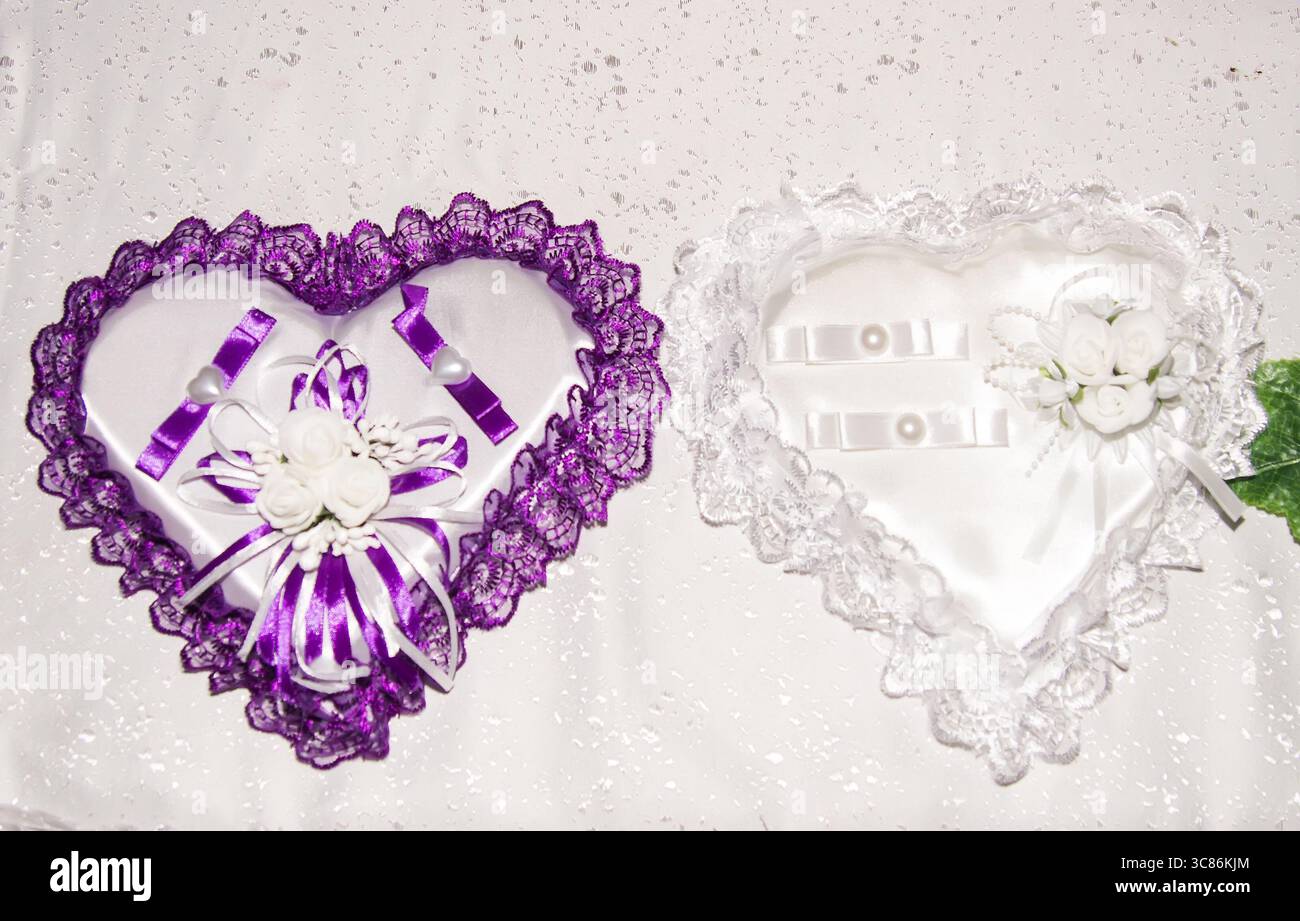 Zwei elegante herzförmige Erinnerungsdosen sind ausgestellt, eine mit lila Spitze und Bändern, die andere in weiß mit Blumenschmuck. Perfec Stockfoto