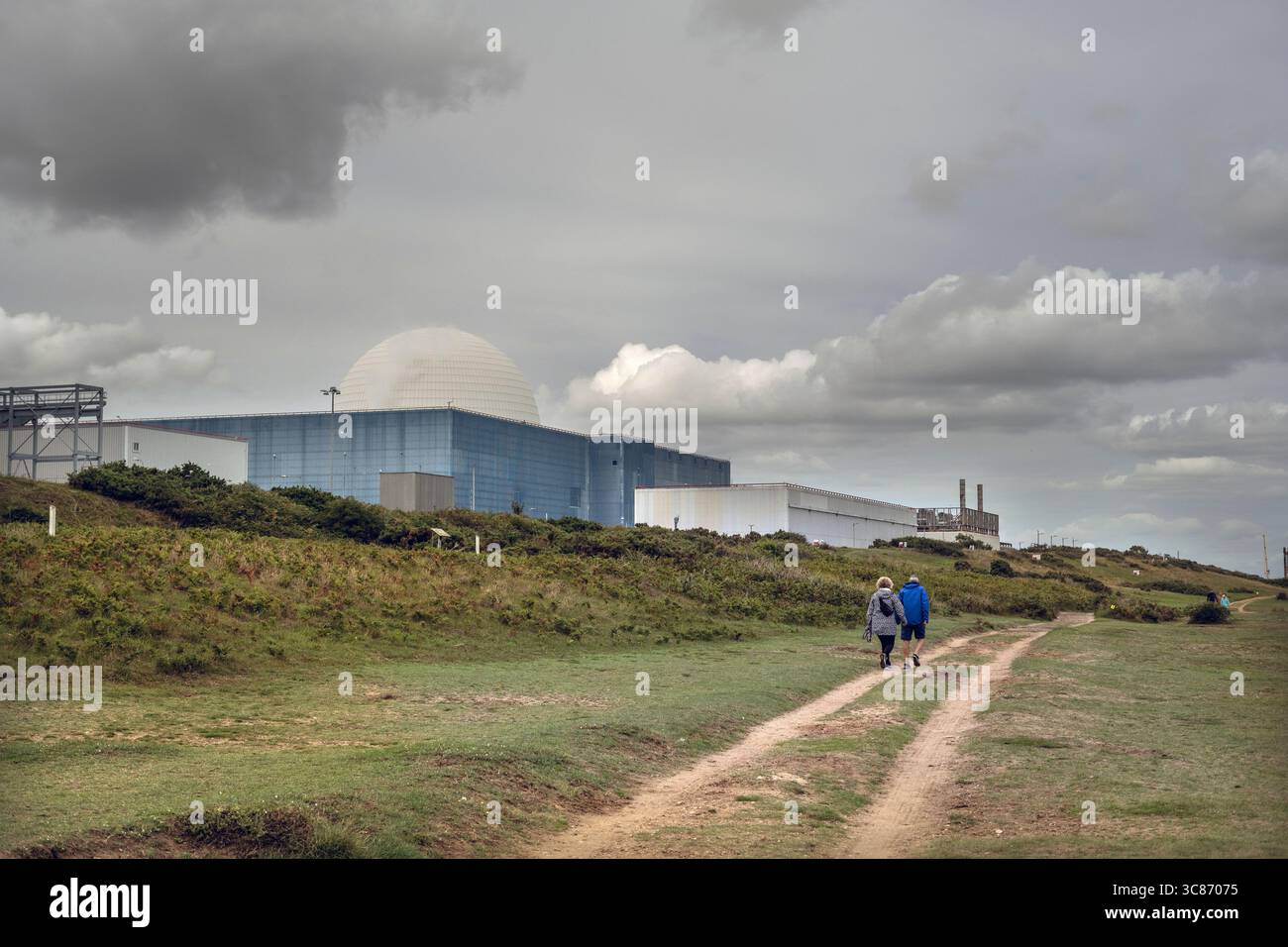 Sie spazieren zusammen auf dem Küstenpfad vorbei an den Atomkraftwerken sizewell A und B in suffolk, england Stockfoto