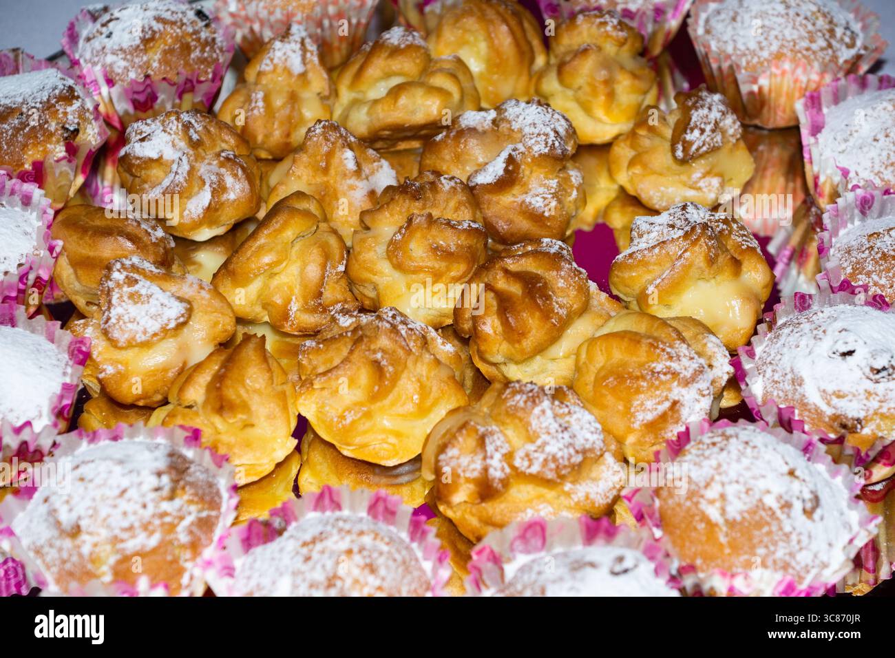 Auf einem farbenfrohen Tablett werden verschiedene süße Gebäckstücke präsentiert, die perfekt für ein Treffen oder eine Feier sind. Die Leckereien sind mit zartem Zuckerguss und Puder versehen Stockfoto