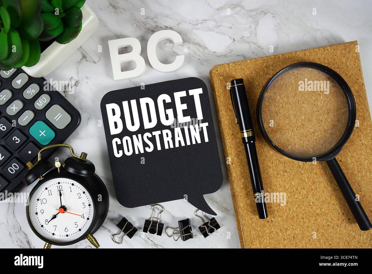 BC Budget Constraint Text mit Rechner, Wecker und Lupe auf Marmorhintergrund Stockfoto