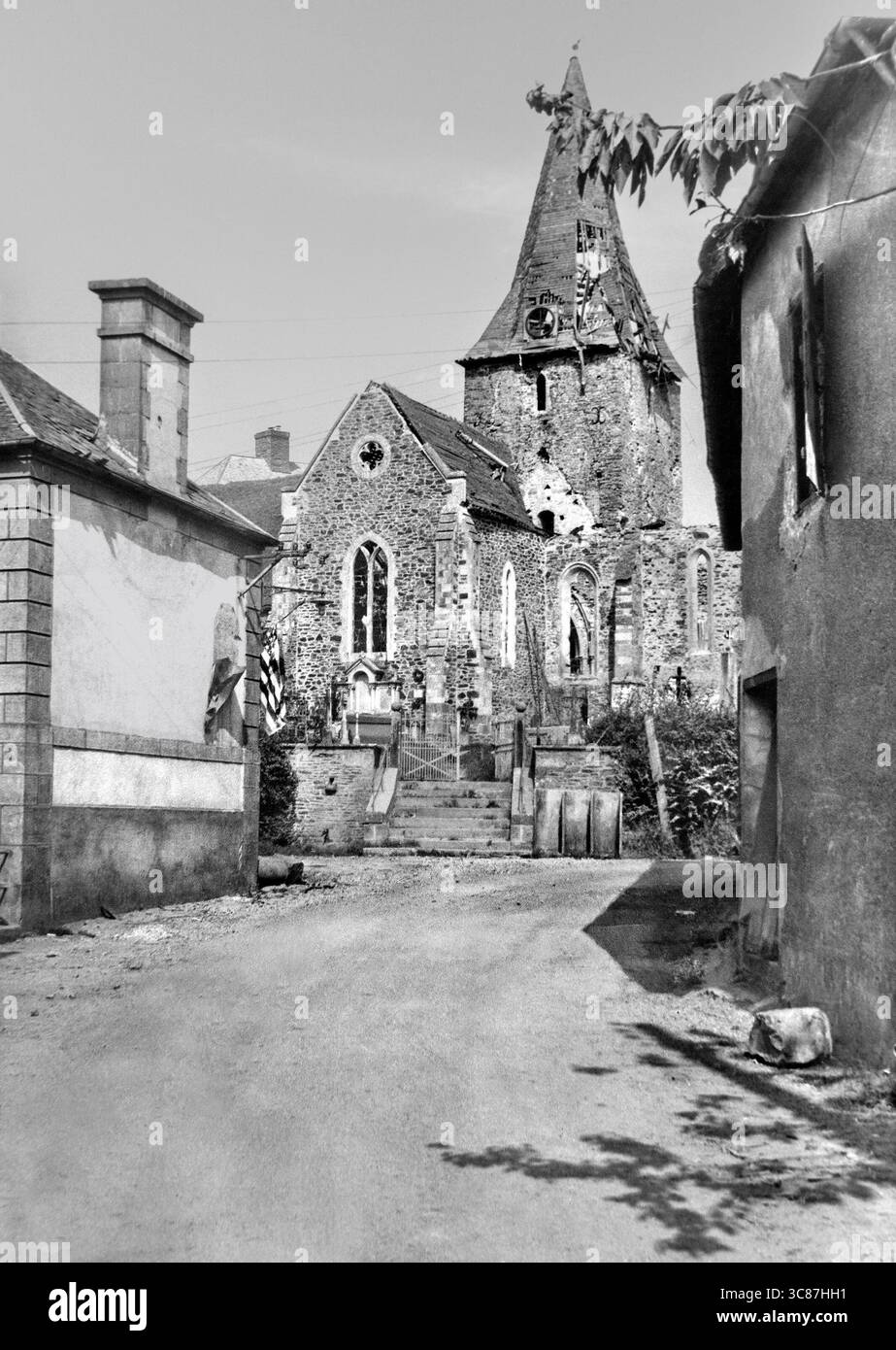1944 Foto einer Kirche in Ruinen mit einer US-Flagge an der Seite eines Gebäudes während der Schlacht von der Normandie und des Ausbruchs in St. Lô, Frankreich Stockfoto
