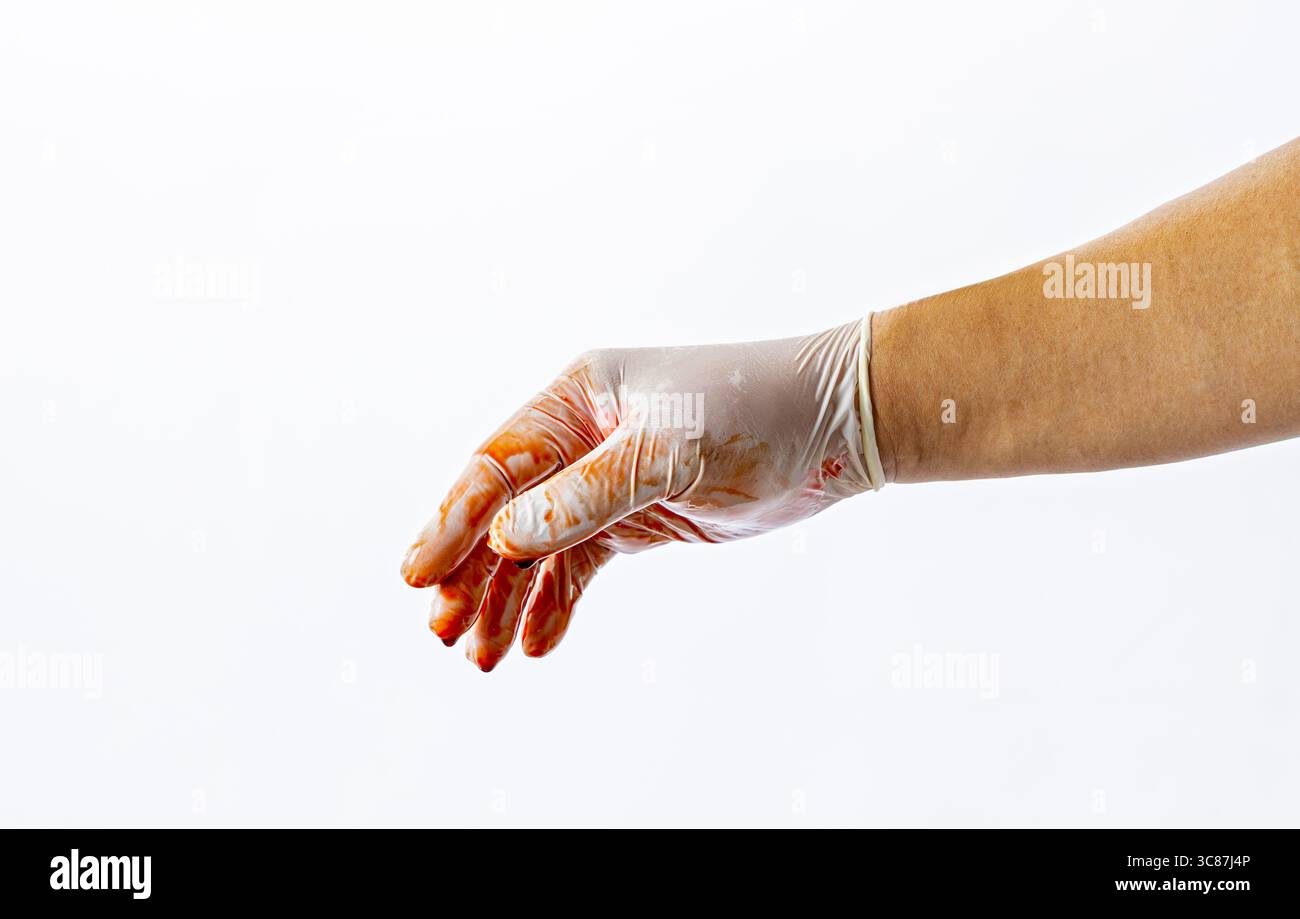 Eine Hand mit Handschuhen, die mit roter Flüssigkeit, möglicherweise Blut, bedeckt ist, wird vor weißem Hintergrund verlängert, was auf einen medizinischen oder forensischen Kontext hindeutet Stockfoto