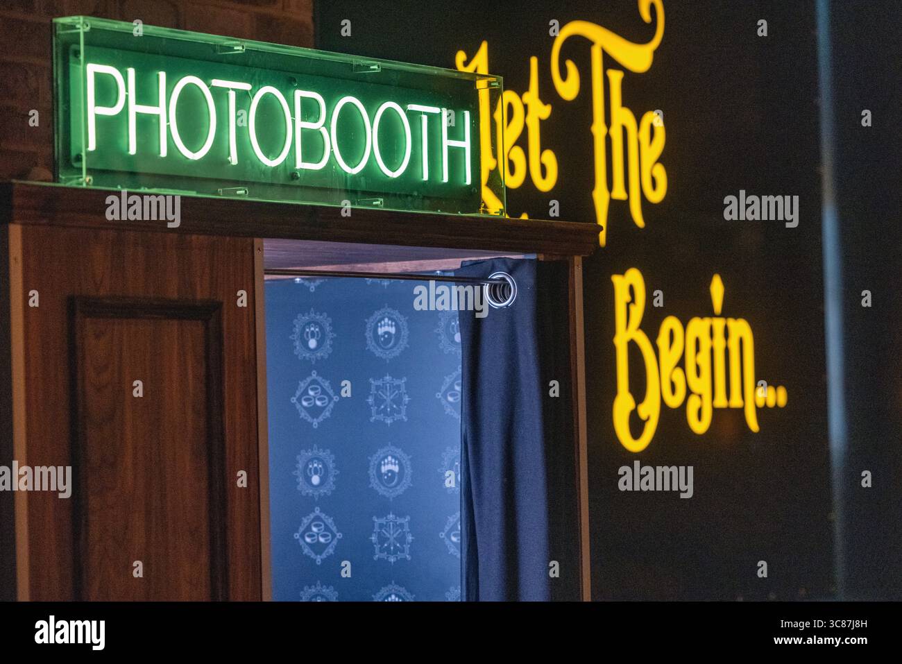 Außenansicht einer Fotokabine mit einem leuchtenden Neonschild, das hell in einer Bar leuchtet. Stockfoto