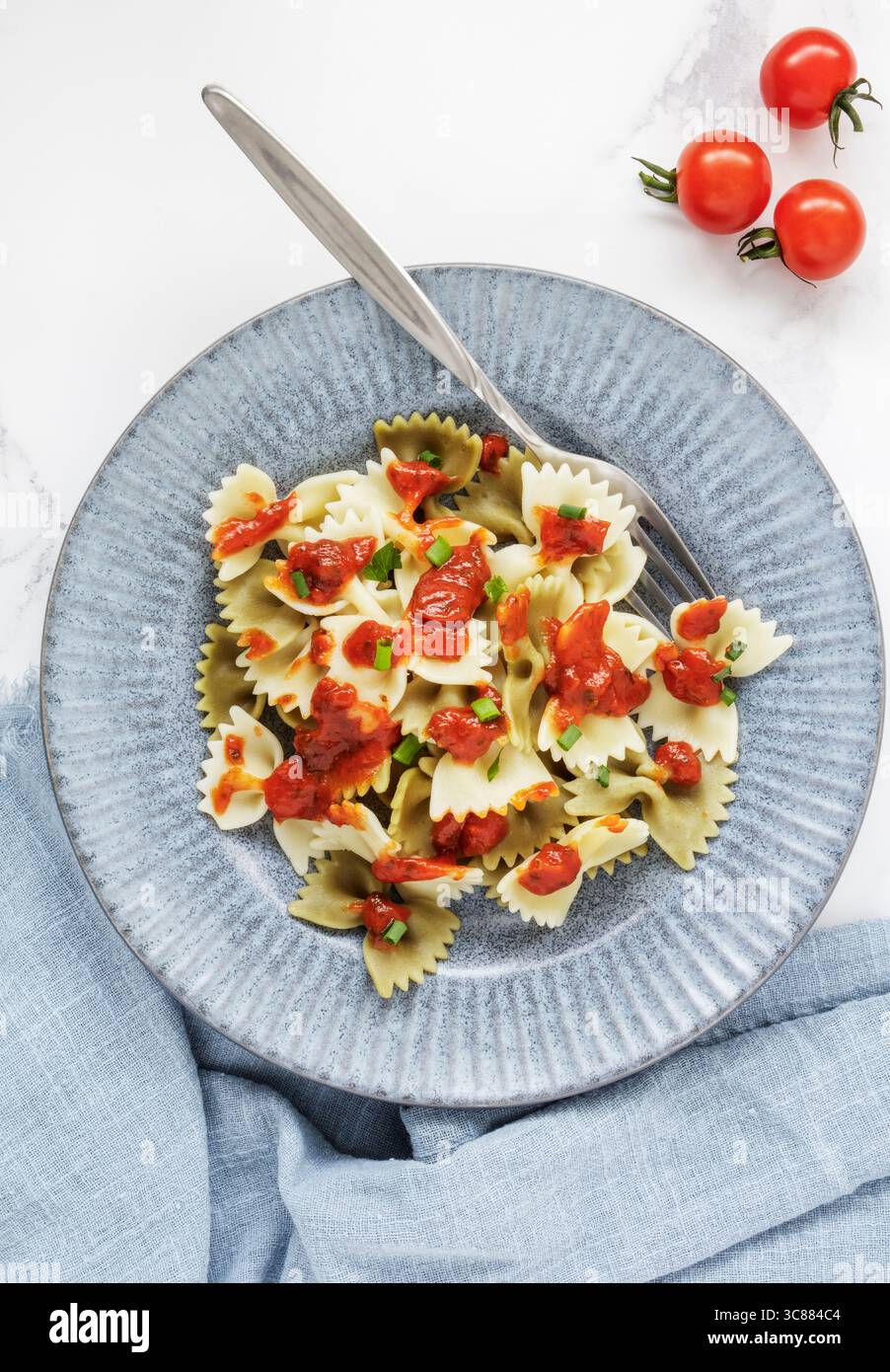 Ein Teller mit gekochter Farfalle-Pasta mit Tomatensauce und frischen Tomaten Stockfoto