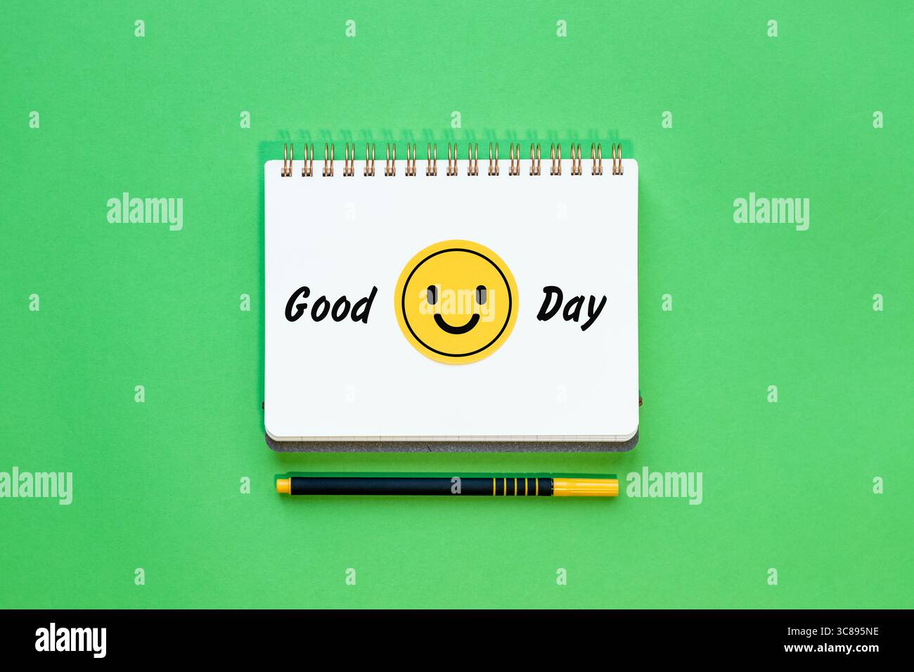 Guten Tag und lächelnd, fröhliches gelbes Smiley-Gesicht-Symbol auf dem Notizblock. Konzept, positiv und negativ. Grüner Hintergrund, Kopierraum. Flache Lagen Stockfoto